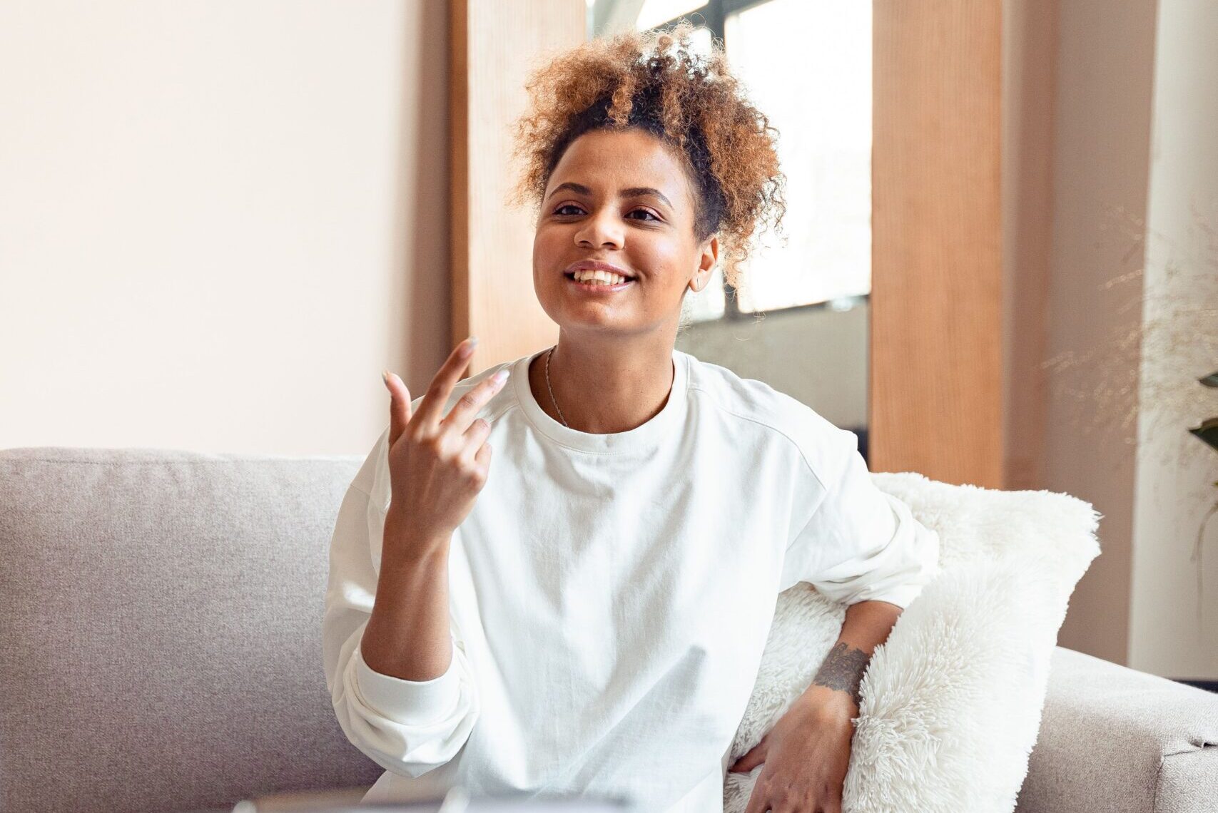 An adult woman is sitting on a sofa and talking at a speech therapy appointment.
