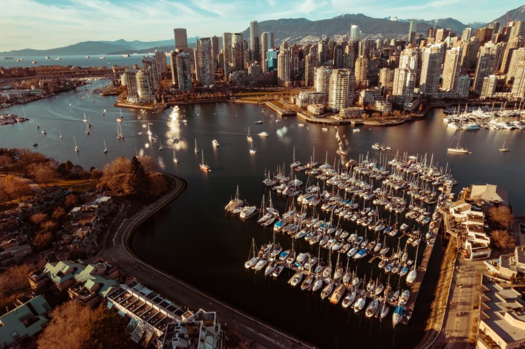 An aerial photo of Granville Island at sunset. The downtown skyline and the pier with boats are visible.